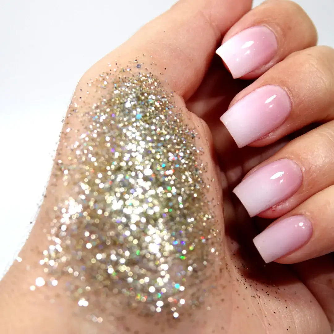 Main de paillettes biodégradables iridescentes et ongles ombré rose blanc pour un look glamour