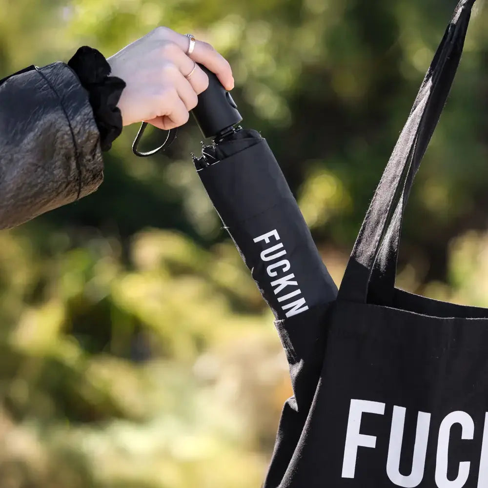 Parapluie Fucking Rain noir avec texte fuck sur manche, clin d’œil à la météo capricieuse