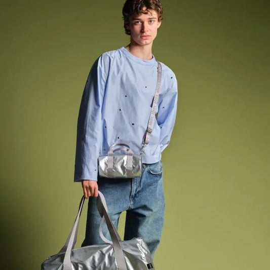 Jeune homme avec sac week-end métallisé petit argenté et sac week-end assorti