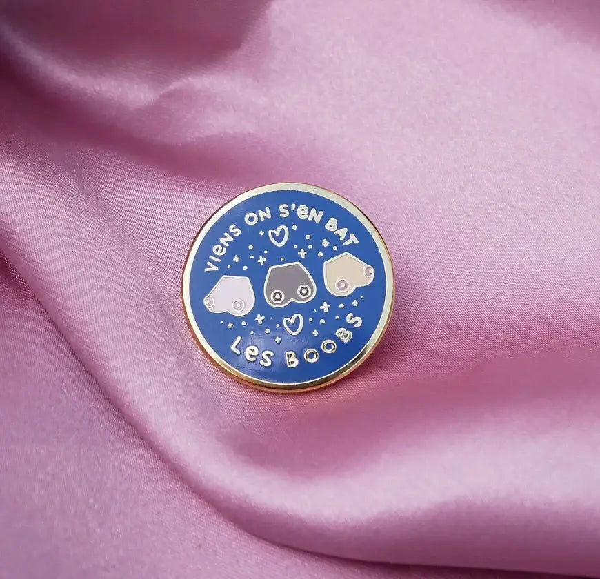 Pin doré rond bleu avec trois seins stylisés et attache papillon pratique