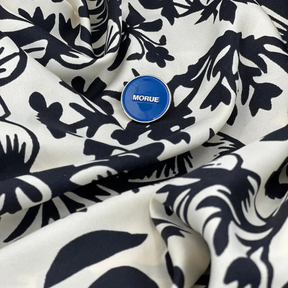 Pin morue bleu circulaire avec touche d’humour sur tissu noir et blanc