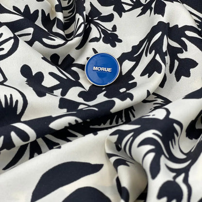 Pin morue bleu circulaire avec touche d’humour sur tissu noir et blanc