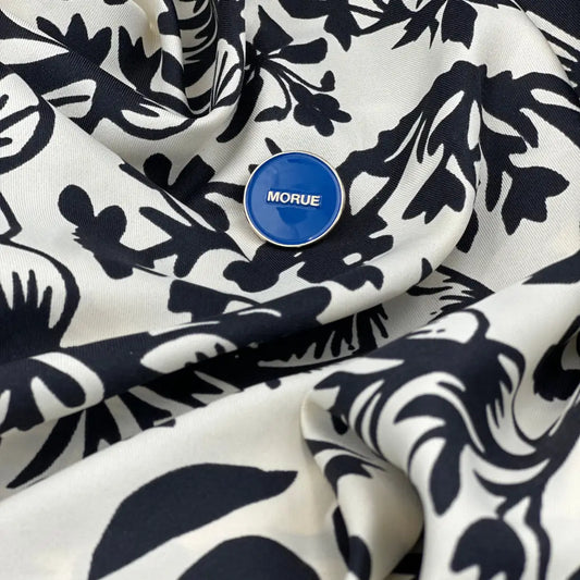 Pin morue bleu circulaire avec touche d’humour sur tissu noir et blanc