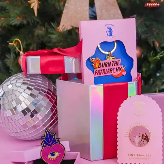 Porte-clé féministe burn the patriarchy avec pin et collier rose près d’un sapin Noël