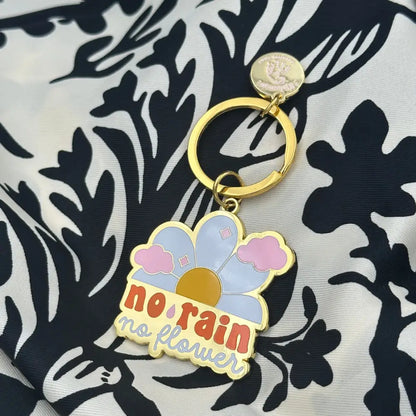 Porte-clé inspirant avec émaillage coloré rain no flowers et fleur en métal doré