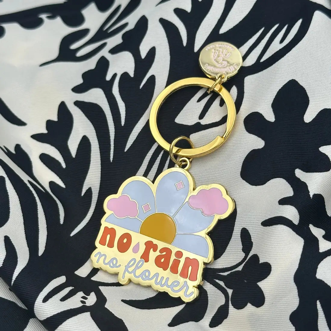 Porte-clé inspirant No Rain No Flowers avec détails dorés et fleur colorée