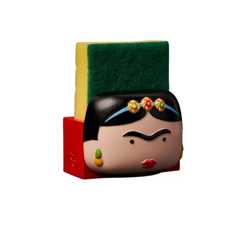 Porte-éponge Frida Kahlo revisité, visage noir et beige aux fleurs colorées, base rouge, éponge verte et jaune, dimension artistique et pratique