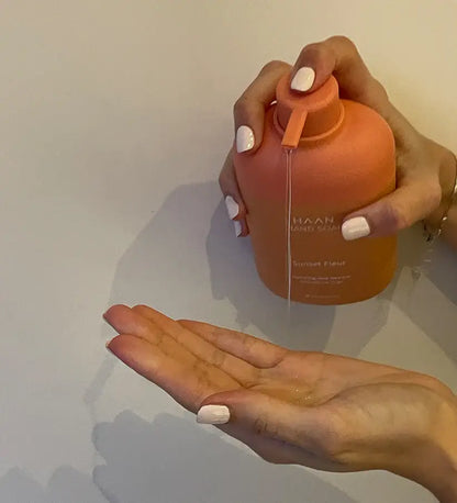 Distributeur savon mains aux probiotiques Sunset Fleur orange en main