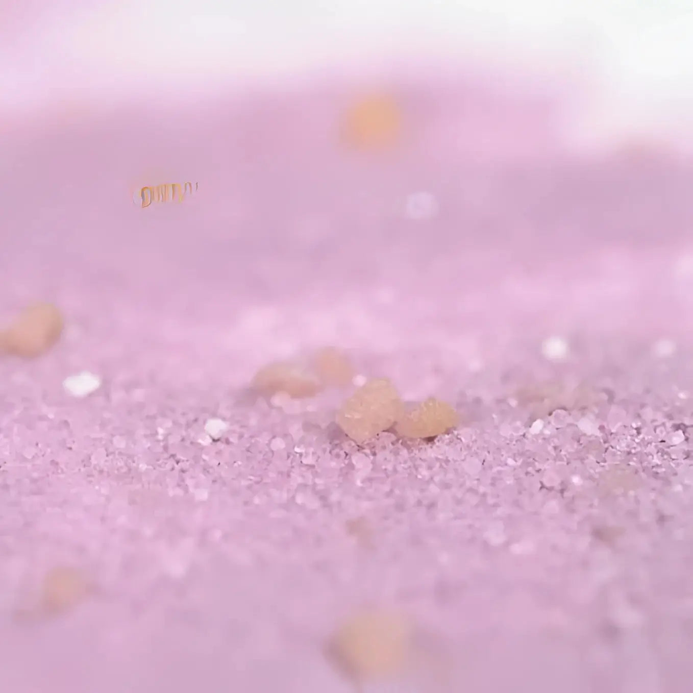 Gros plan sur cristaux de sucre rose et grumeaux brun clair pour Sels De Bain Crépitants Enfant- Rose, formulation douce pour peau fragile