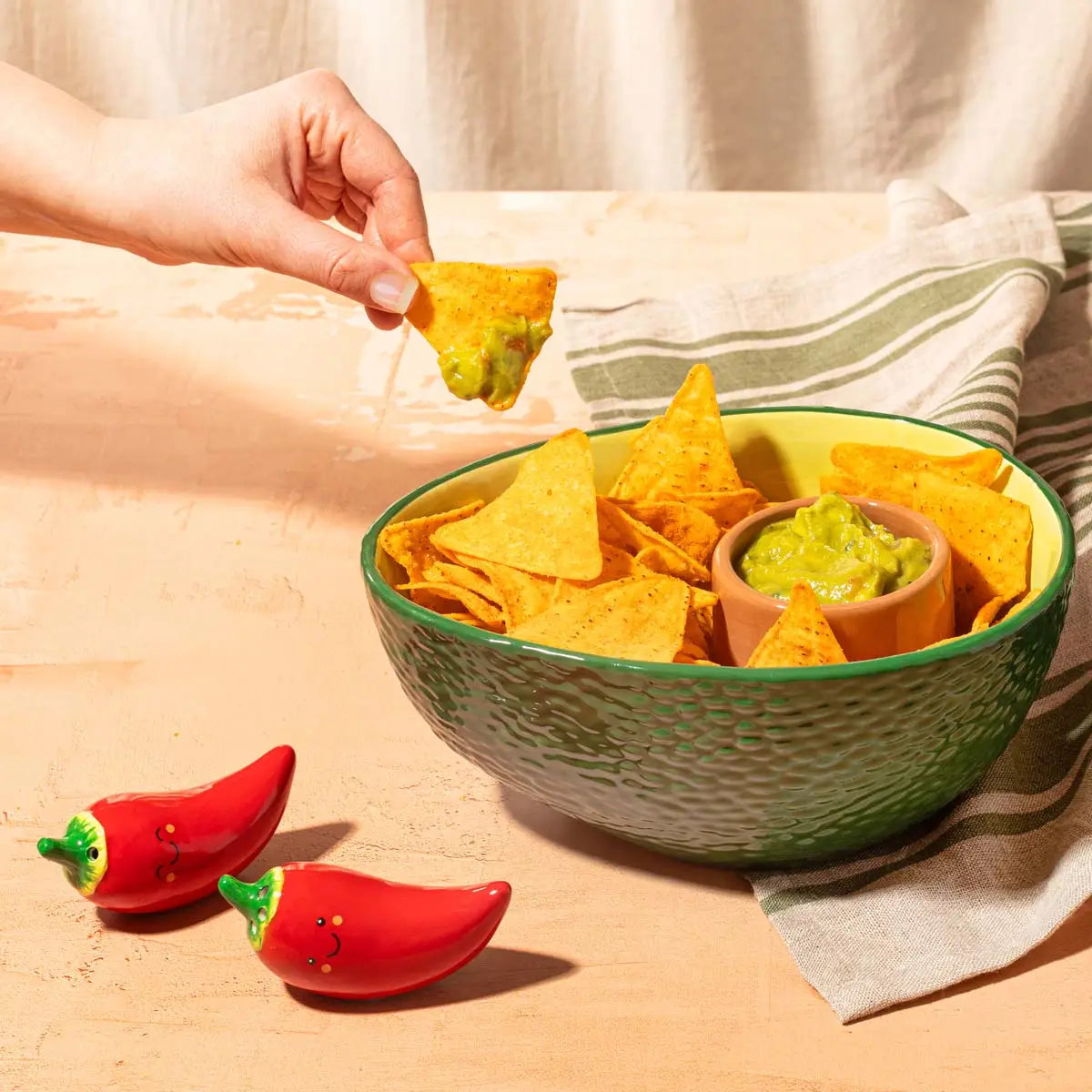Bol apéritif vert texturé rempli de chips jaunes et guacamole terracotta, forme d’avocat