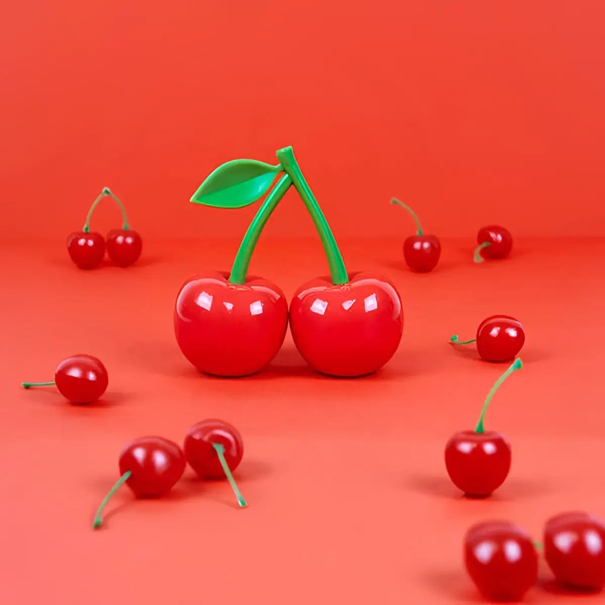 Cerises rouges brillantes en plastique avec tiges vertes sur fond orange