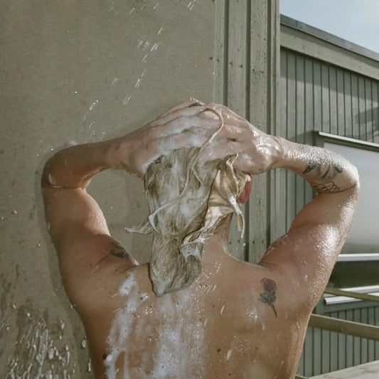 Person lavant cheveux blonds avec shampoing liquide bouleau pour cuir chevelu sain