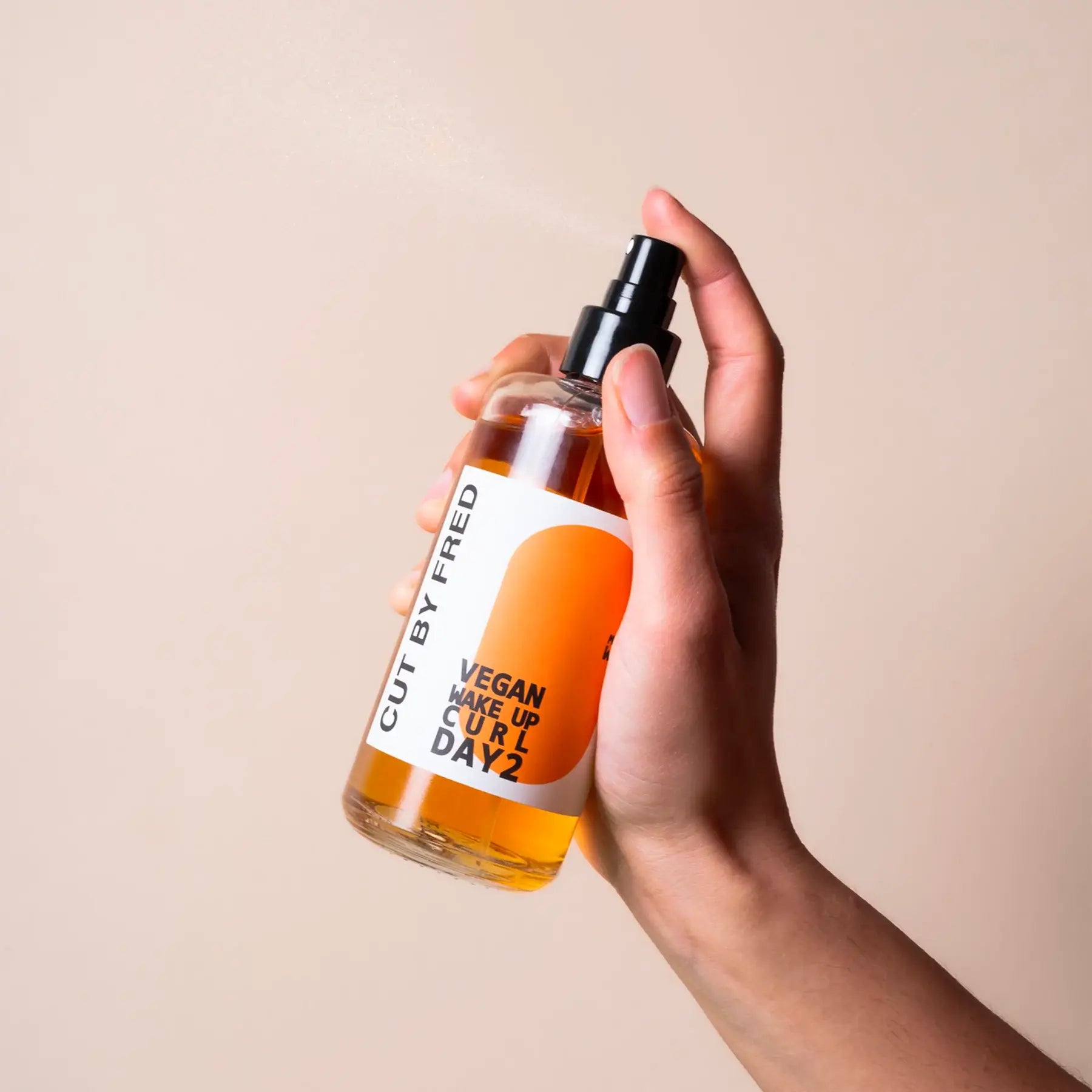 Main en tenant spray hydratant pour boucles redessinées à la fleur d’oranger