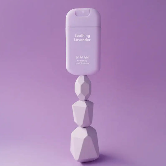 Alt text d’un spray mains lavande apaisante en bouteille violette sur des pierres