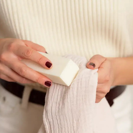 Mains tenant un savon détachant et un tissu texturé pour le détachant textile