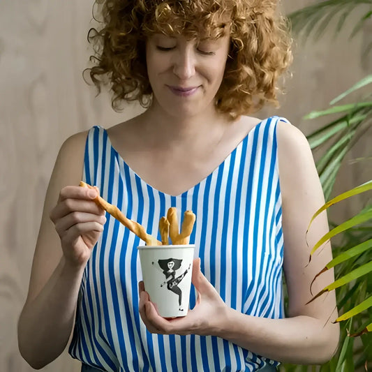 Femme en haut rayé bleu et blanc tenant tasse Girl Power et bâtonnets