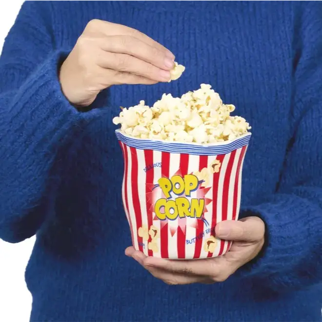 Personne tenant un seau à popcorn rouge et blanc pour une ambiance cinéma