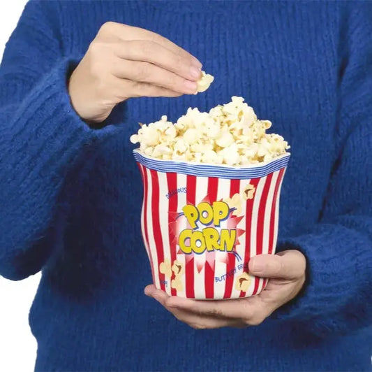 Personne tenant un seau à popcorn rayé rouge et blanc, ambiance cinéma humoristique