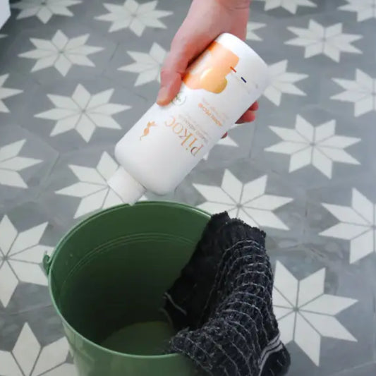 Vinaigre jasmin pêche 500 mL, bouteille en plastique blanc versant dans un seau vert